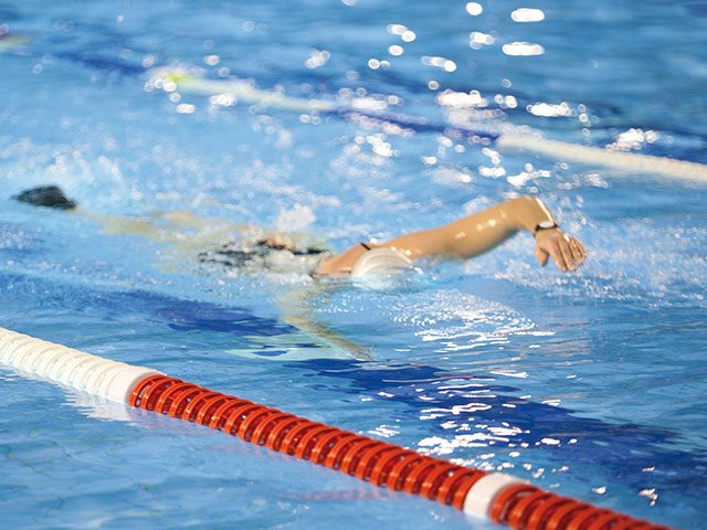 Frau schwimmt im Sportbecken des Bad Innenbereichs