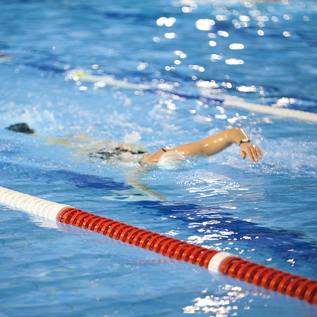 Frau schwimmt im Sportbecken des Bad Innenbereichs