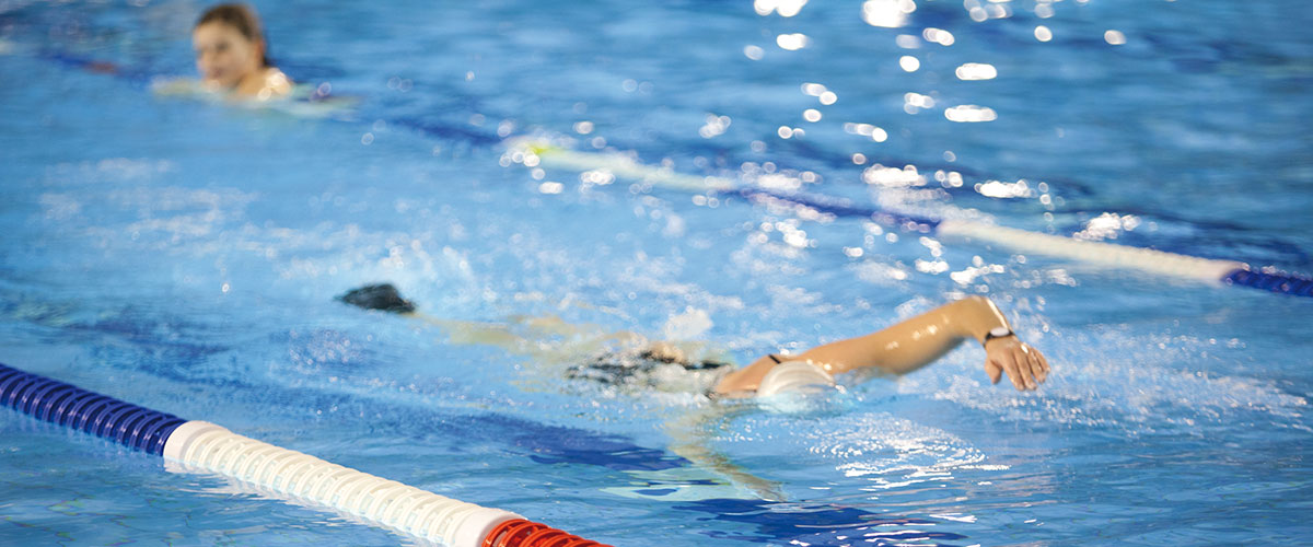 Frau schwimmt im Sportbecken des Bad Innenbereichs