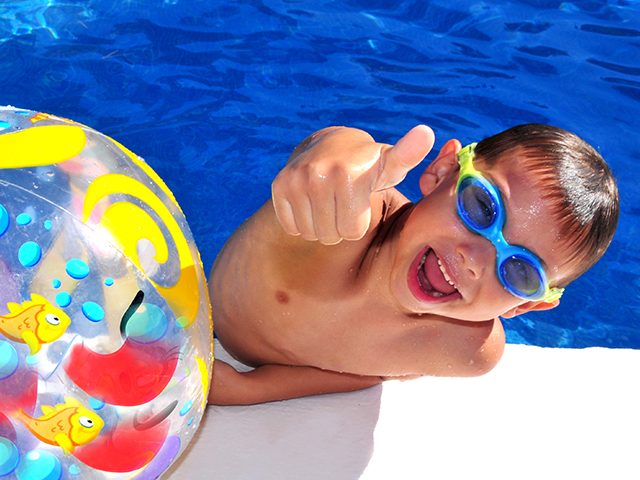 Junge mit Taucherbrille und Wasserball mit Daumen nach oben