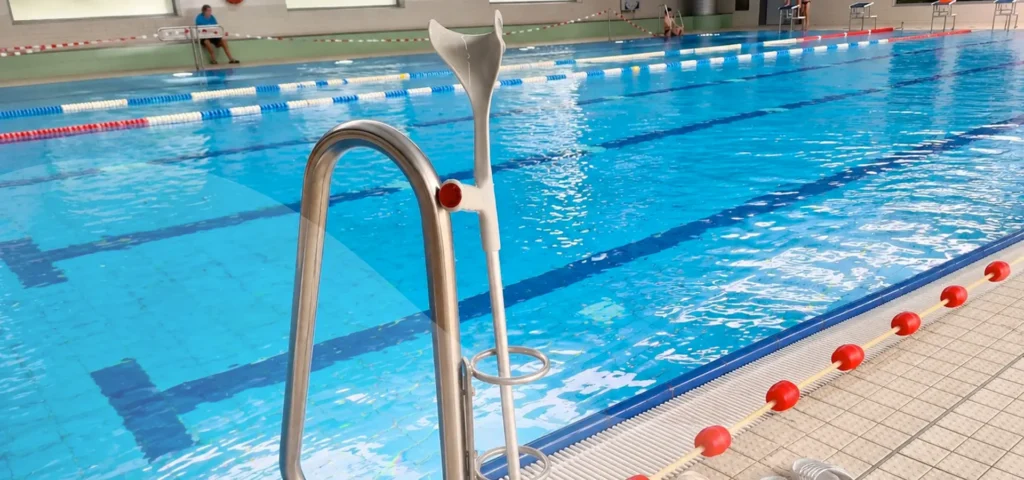 Gehstock in Haltefunktion an Einstiegstreppe zum Schwimmbecken