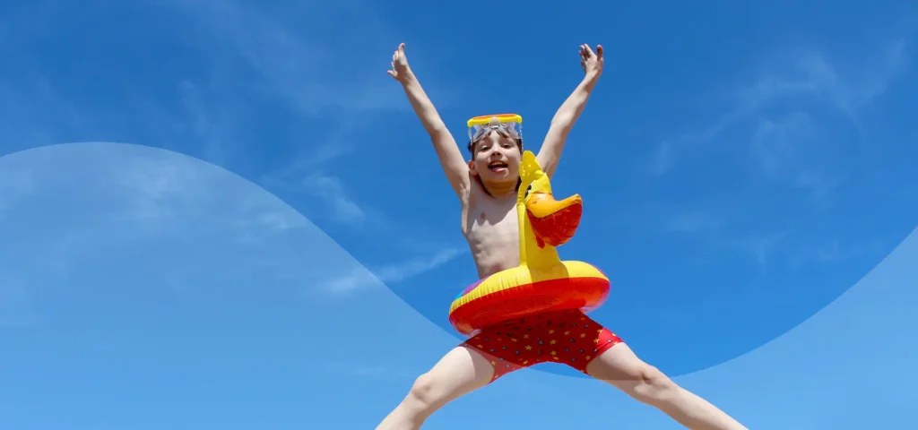 Junge springt in die Luft in Badesachen und Schwimmreifen