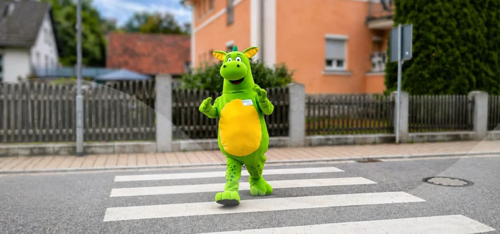 Maskottchen Cabriolino der grüne Drache läuft über einen Zebrastreifen