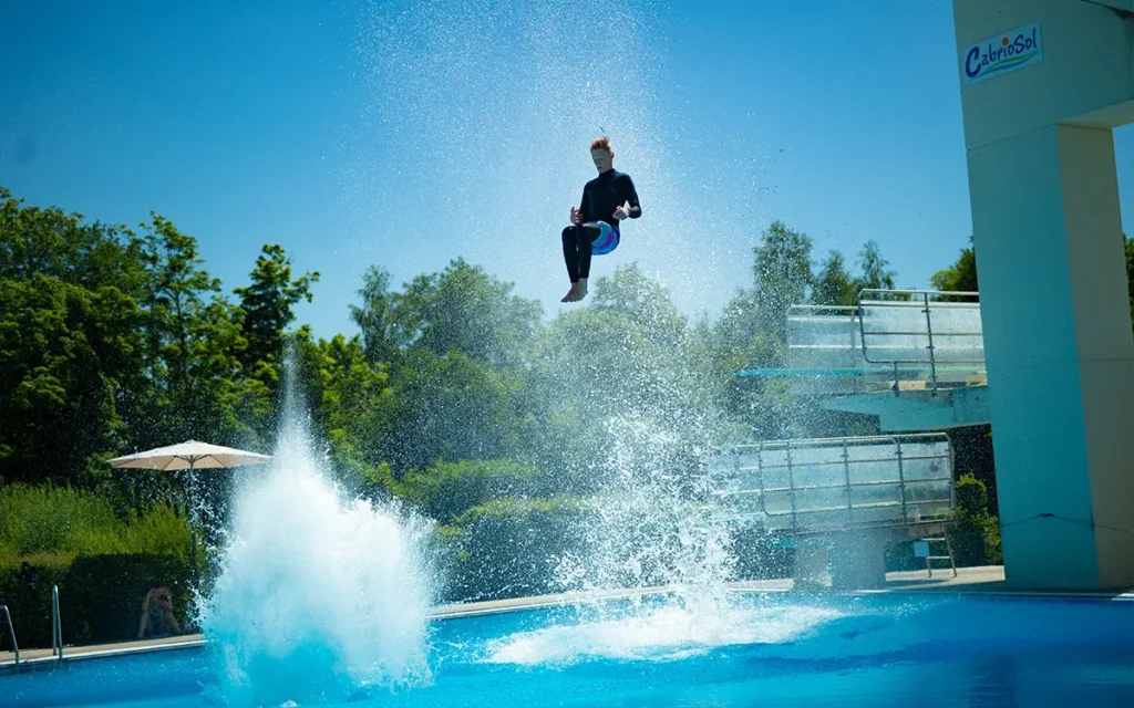 Person springt vom Sprungturm ins Wasser