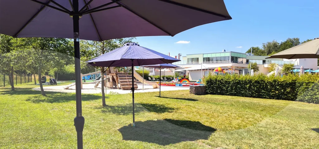 Sonnenschrime auf Wiesenfläche, neben Kinderspielplatz