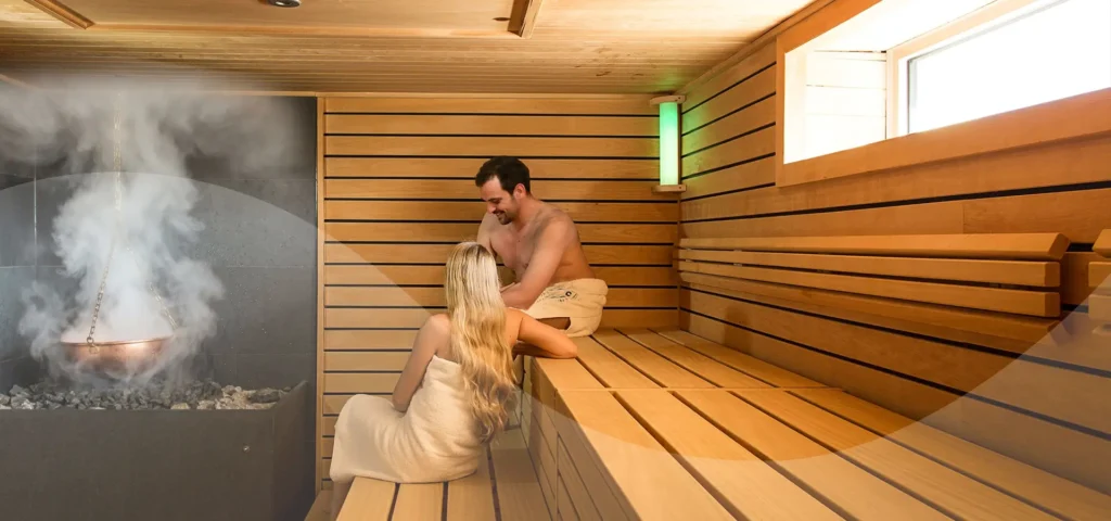 Mann und Frau sitzen in einer Sauna mit Dampfkessel
